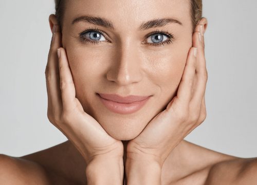 Skin care. Beautiful woman with healthy facial skin touching hands moisturized face skin, on light grey background | Avail Aesthetics in Cary, Raleigh & Wake Forest, NC
