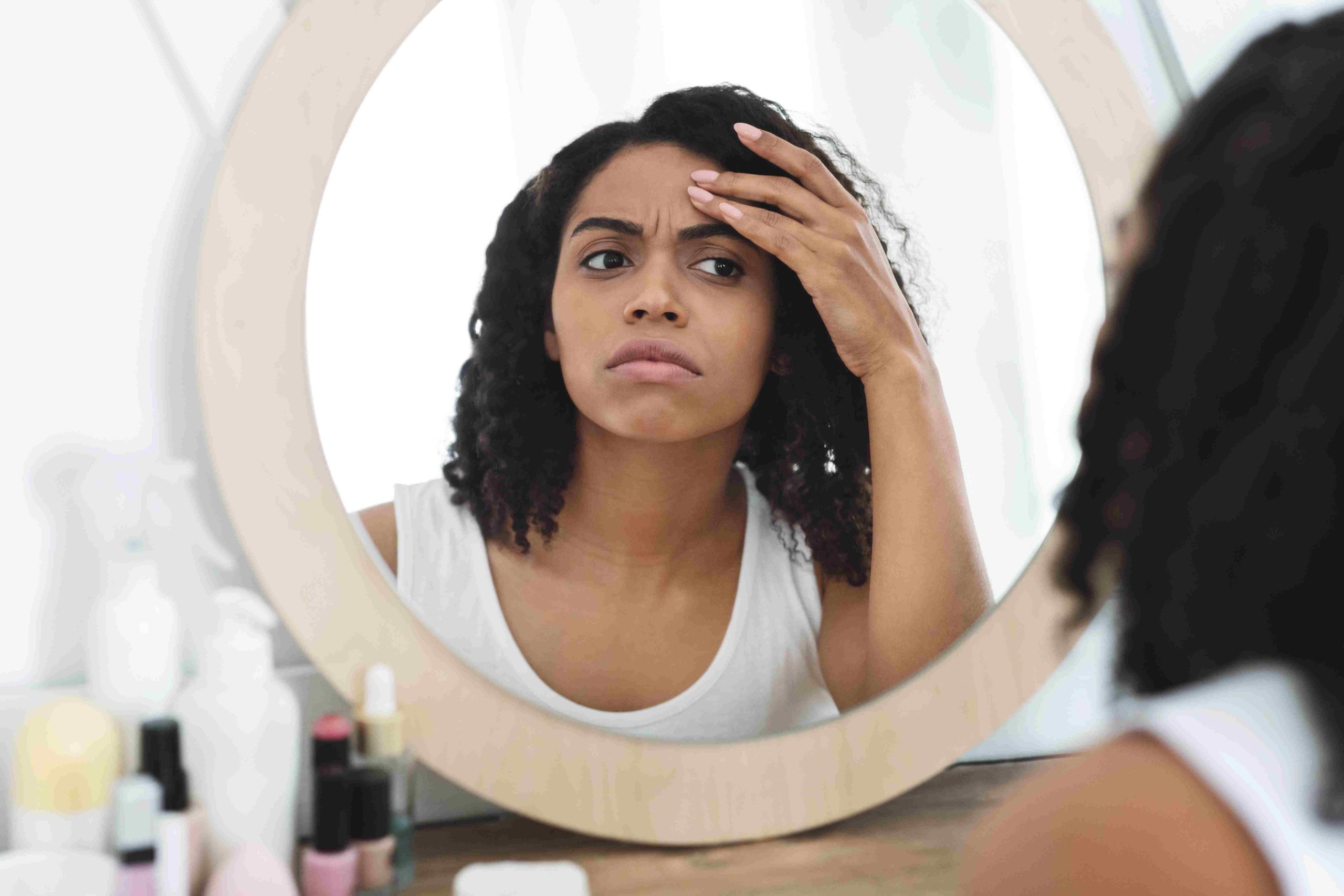 Young Woman Checking Her Wrinkles by Looking At Mirror | Avail Aesthetics in Cary, NC